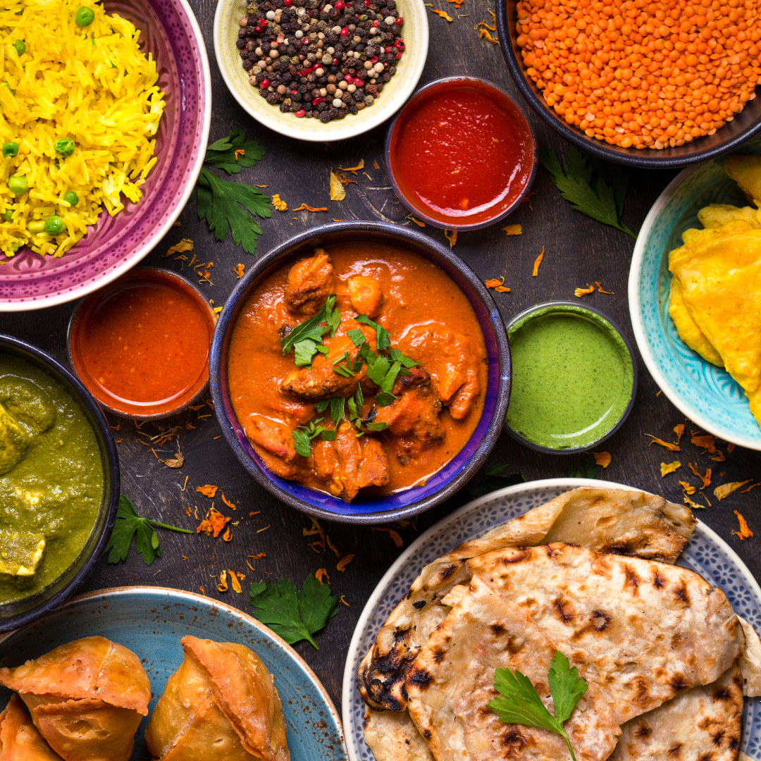 A photo of different Indian dishes, including a curry, naans, and samosas. The dishes are all made with a variety of Indian spices, such as turmeric, coriander, and cumin.